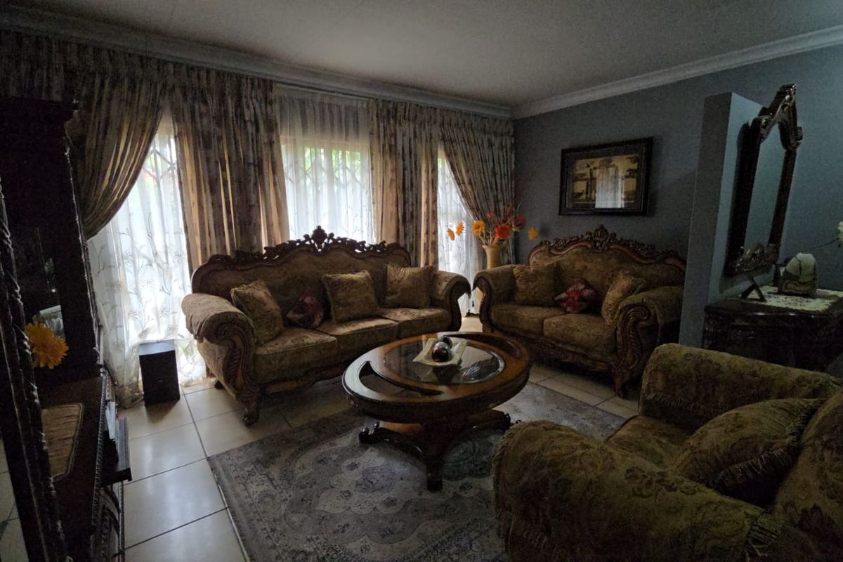 A formal living room featuring tiled flooring and decorative cornice detailing, offering a traditional layout with ample natural light through large window treatments.
