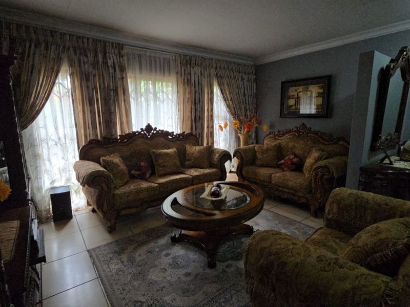 A formal living room featuring tiled flooring and decorative cornice detailing, offering a traditional layout with ample natural light through large window treatments.