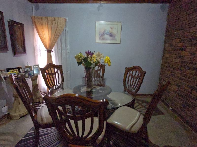Dining room featuring an exposed brick accent wall and timber ceiling trim, requiring cosmetic updates to improve the overall finish.