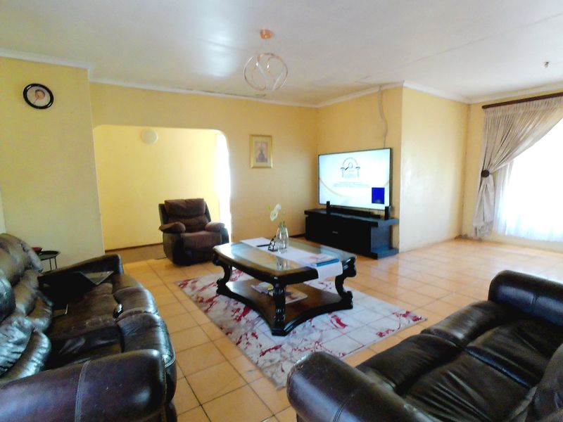 Spacious living room featuring tiled flooring and natural light, currently requiring cosmetic updates to the ceiling and wall finishes.