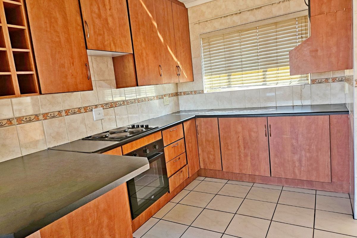 A functional kitchen featuring laminate cabinetry, built-in oven, electric hob, and tiled flooring, offering a clean space ready for modern updates.