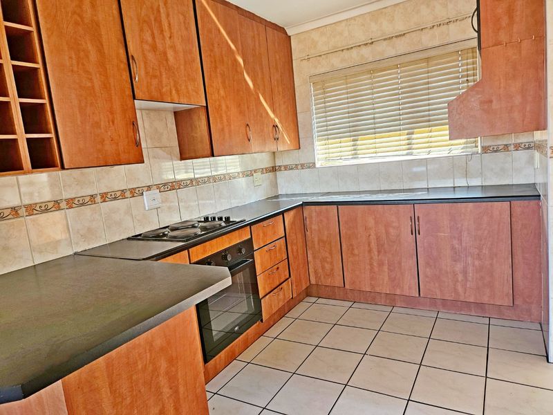 A functional kitchen featuring laminate cabinetry, built-in oven, electric hob, and tiled flooring, offering a clean space ready for modern updates.
