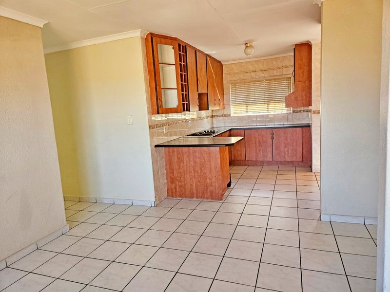 A functional kitchen featuring built-in wooden cabinetry, laminate countertops, a tiled backsplash, and ceramic floor tiles, offering a clean and practical workspace.