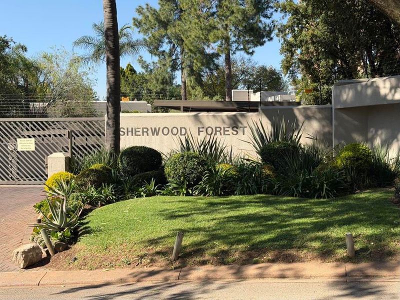 Front entrance view of Sherwood Forest featuring a secure boundary wall, electric fencing, and a well-maintained landscaped garden.