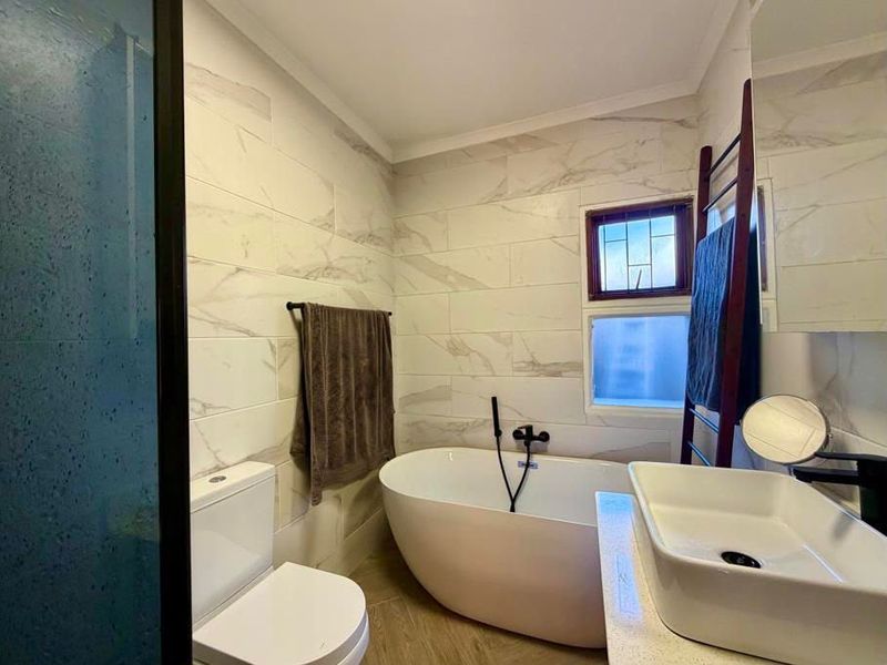 Modern bathroom featuring a freestanding bathtub, vessel sink, and contemporary marble-look wall tiling with a shower enclosure.