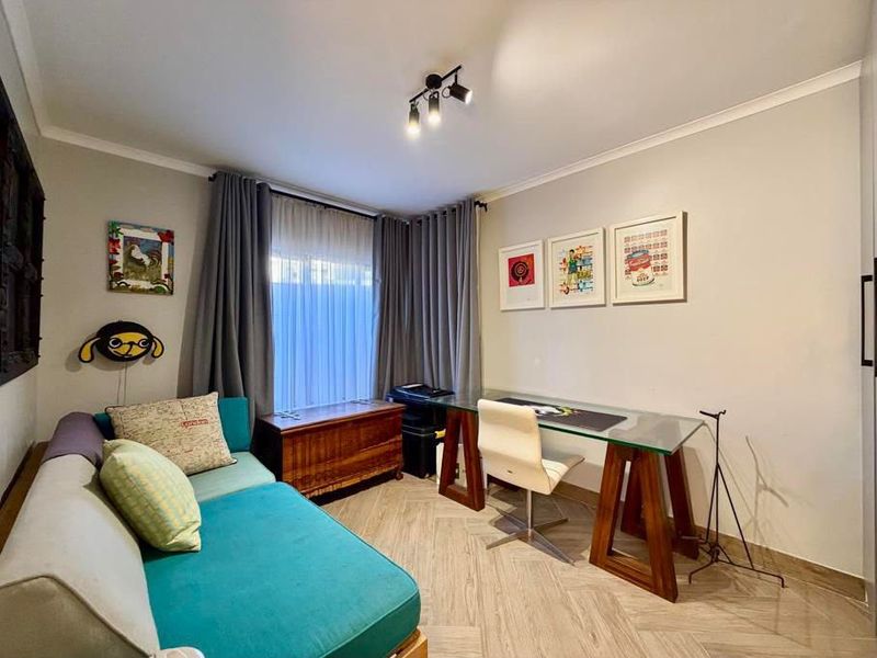 A functional home office space featuring modern track lighting and stylish herringbone flooring, providing a comfortable and well-lit area for work.