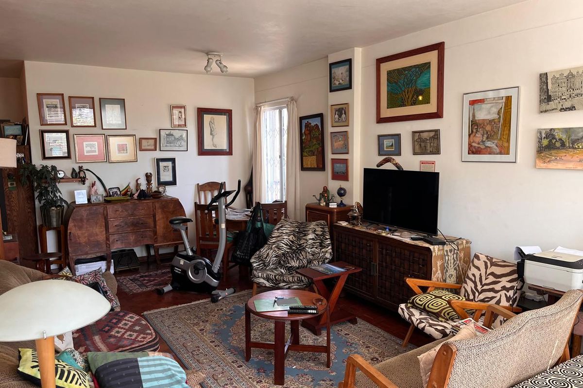 A cozy living room featuring hardwood flooring and a window with a security gate, offering a comfortable and lived-in atmosphere.
