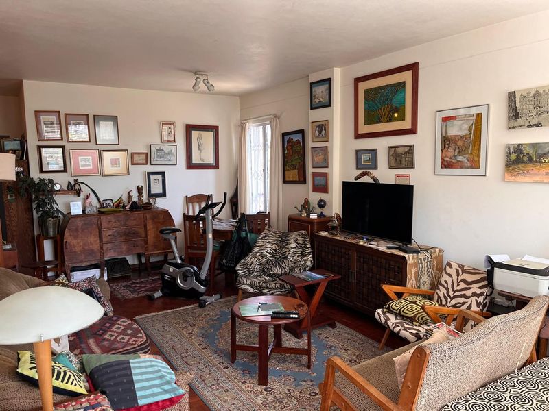 A cozy living room featuring hardwood flooring and a window with a security gate, offering a comfortable and lived-in atmosphere.
