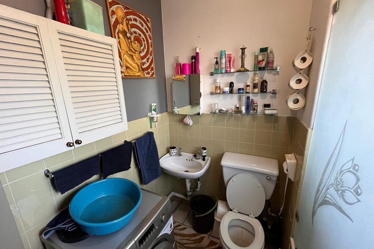 Compact bathroom featuring a wall-mounted basin, toilet, and built-in storage cabinetry with tiled splashbacks.