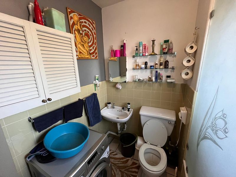 Compact bathroom featuring a wall-mounted basin, toilet, and built-in storage cabinetry with tiled splashbacks.
