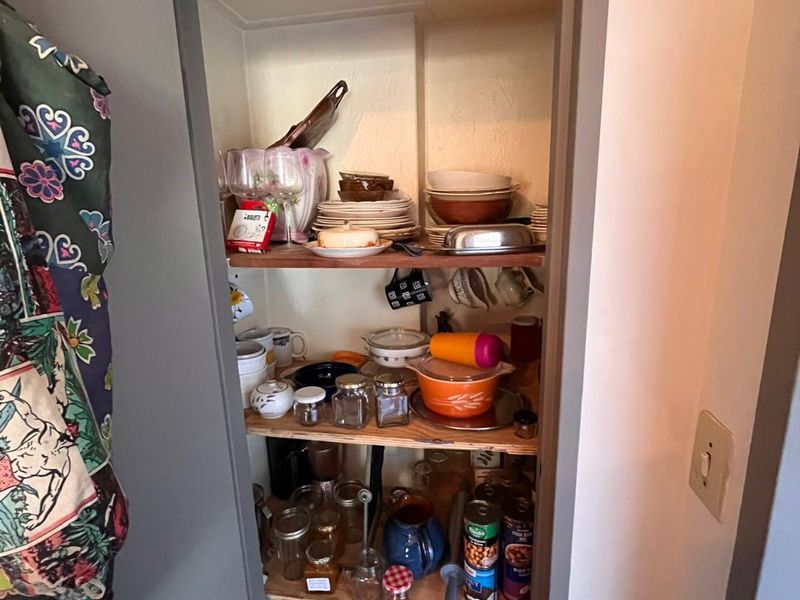 A compact built-in pantry or storage cupboard featuring multiple wooden shelves for organized kitchen storage.