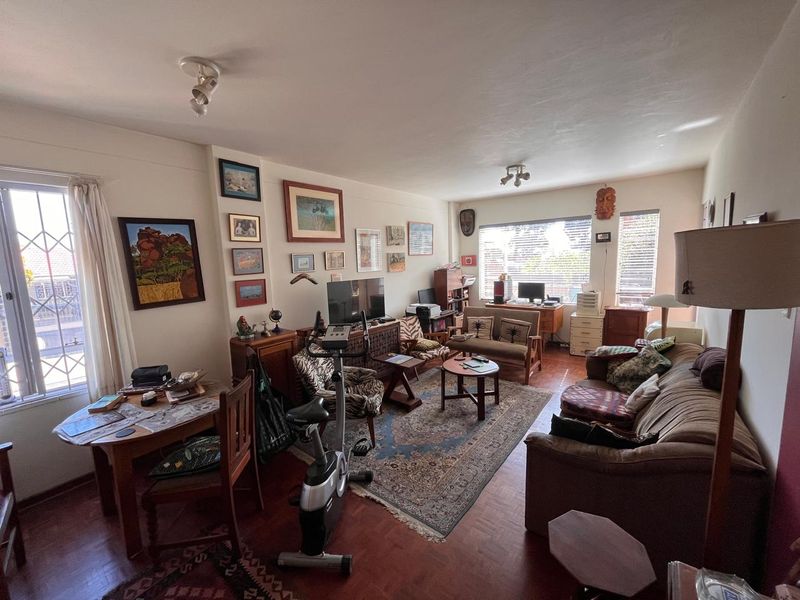 Spacious living room featuring classic parquet flooring, large windows with security bars, and adjustable ceiling spotlights, offering a comfortable and functional layout.