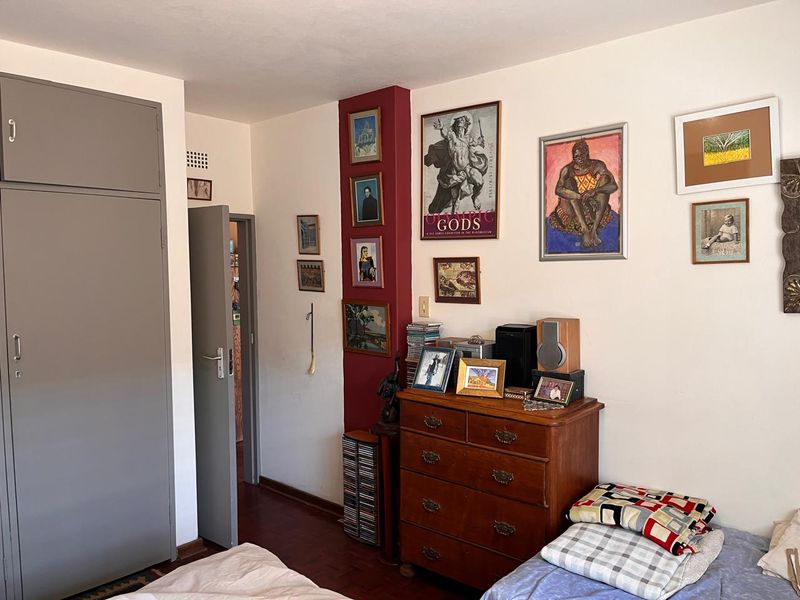A bedroom featuring parquet flooring and a built-in wardrobe, offering a functional space with potential for modern updates.