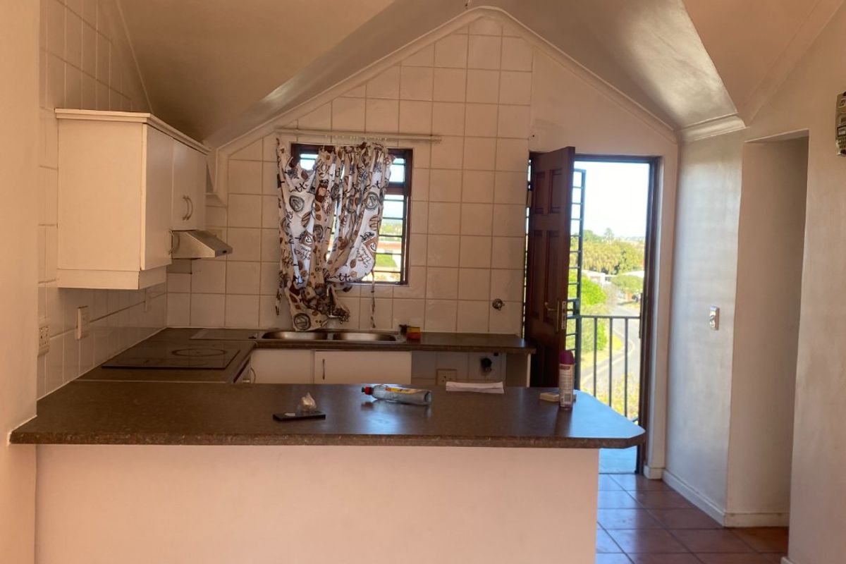 A functional kitchen featuring a breakfast bar, built-in hob, extractor fan, and direct access to an outdoor balcony area.