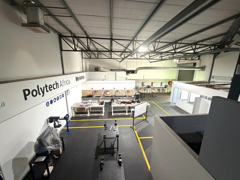 Spacious industrial workshop featuring high ceilings with exposed steel trusses, durable epoxy flooring, and integrated ventilation systems, suitable for various technical or manufacturing operations.