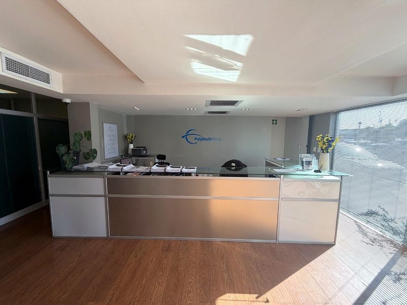 Professional reception area featuring a modern built-in desk, recessed lighting, ducted air conditioning, and large windows with blinds.