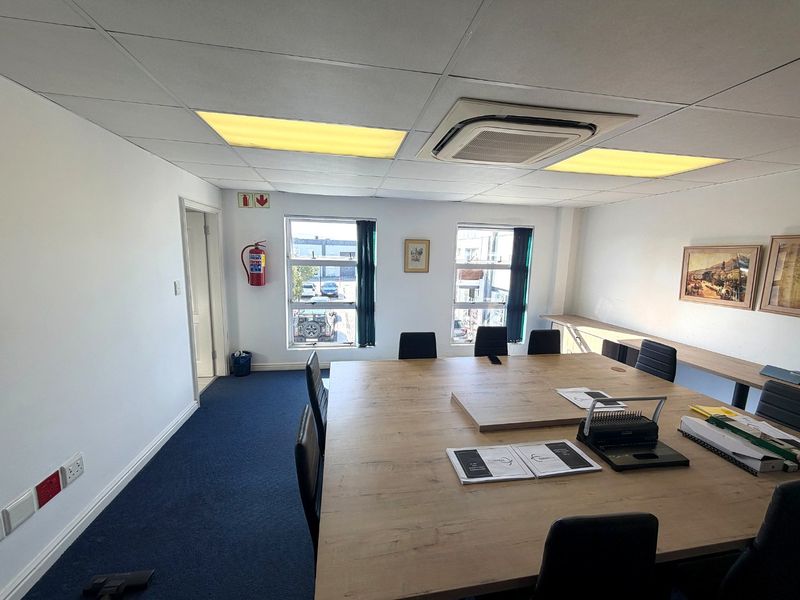 A functional office space featuring a suspended ceiling, integrated cassette air conditioning, carpeted flooring, and a built-in desk area.