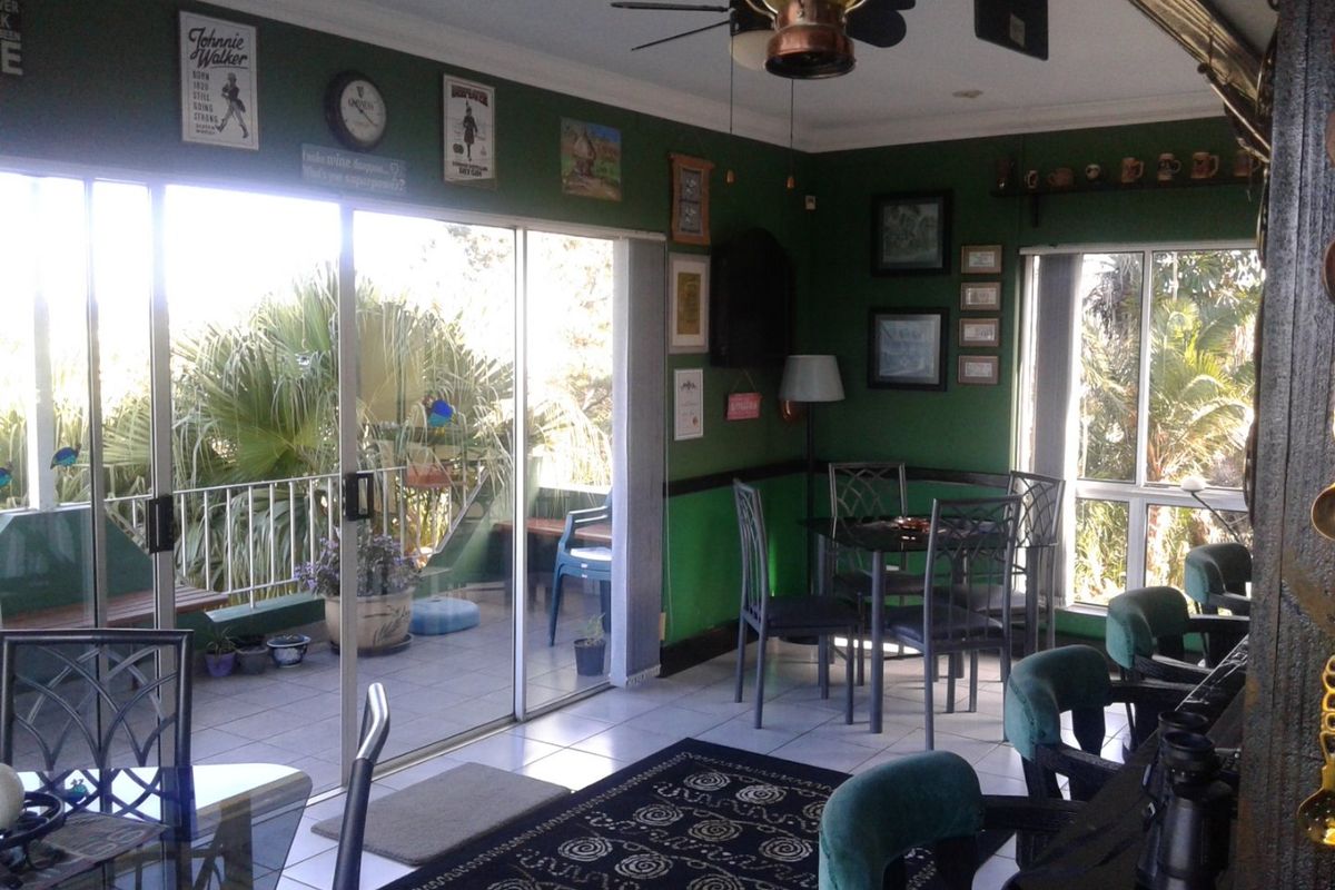 Living area featuring tiled flooring, ceiling fan, and large sliding glass doors providing access to an outdoor balcony space.