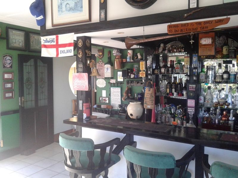 A dedicated home bar area featuring a built-in counter, mirrored shelving, and traditional timber detailing, creating a classic pub-style atmosphere.