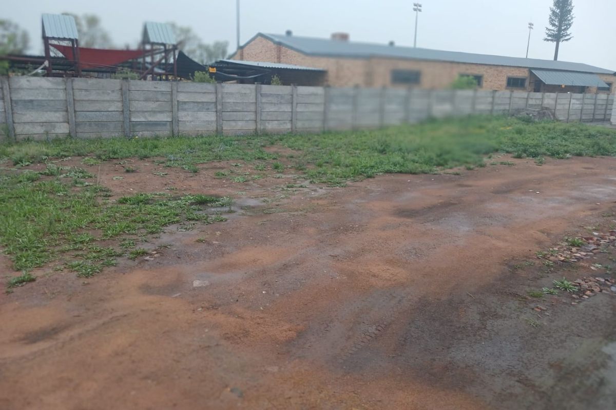 A view of a vacant residential plot featuring an unpaved surface and a precast concrete boundary wall.