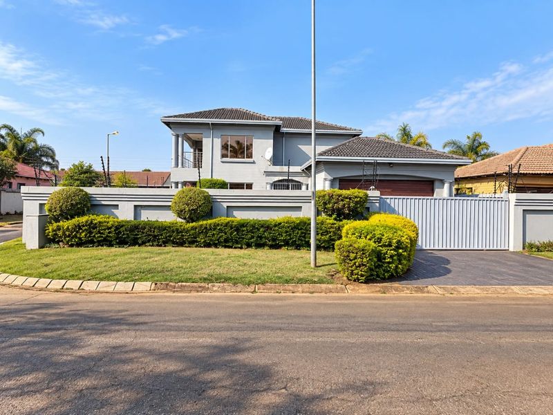 Front view of a double-story residential property featuring a tiled roof, paved driveway, secure boundary wall with electric fencing, and a garage.