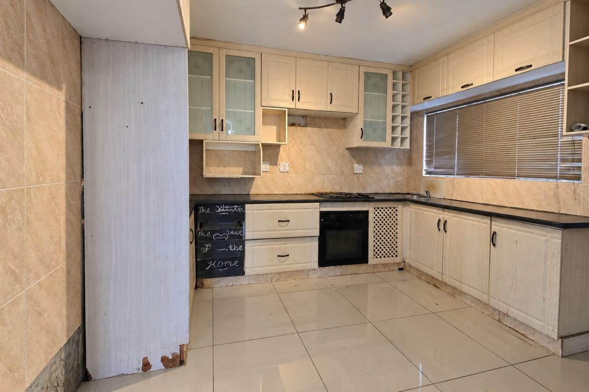 A functional kitchen featuring built-in cabinetry, black stone countertops, a built-in oven, and a gas hob, finished with ceramic floor tiles and tiled backsplash.