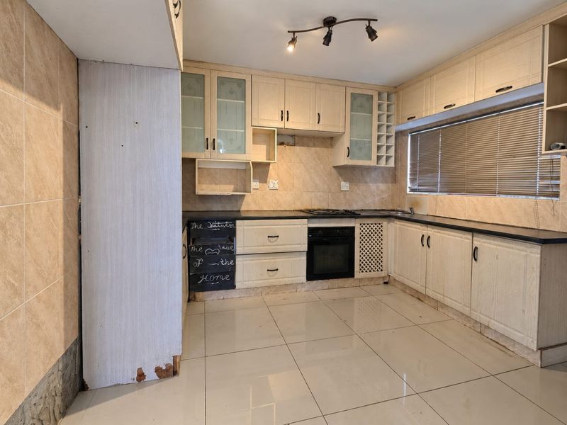 A functional kitchen featuring built-in cabinetry, black stone countertops, a built-in oven, and a gas hob, finished with ceramic floor tiles and tiled backsplash.