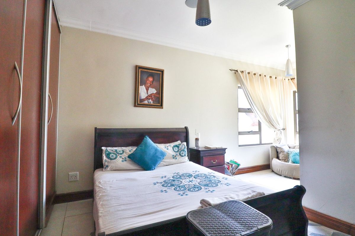 A functional bedroom featuring built-in wardrobes, tiled flooring, and a ceiling fan, offering a comfortable and practical living space.