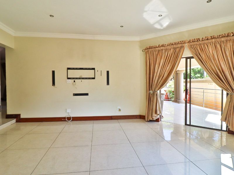 Spacious living area featuring neutral tiled flooring, recessed lighting, and direct access to an outdoor patio through a sliding glass door.