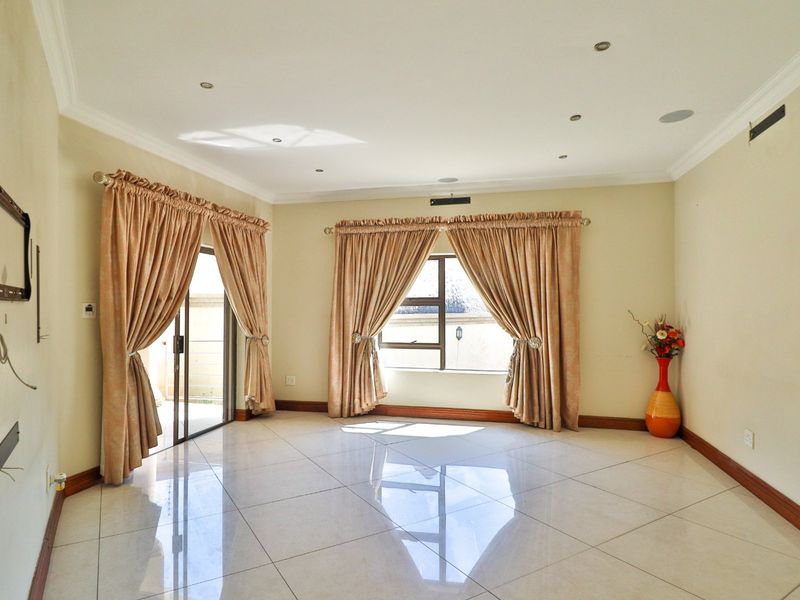 Spacious living area featuring polished tiled flooring, recessed downlighting, and large windows with sliding door access to the exterior.