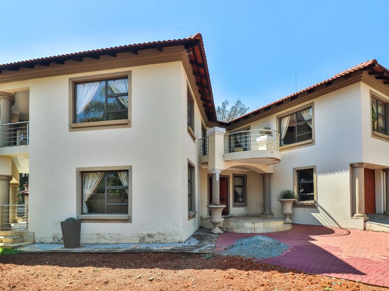 Rear elevation of a two-story house featuring a balcony with stainless steel balustrades, tiled roof, and paved patio area.