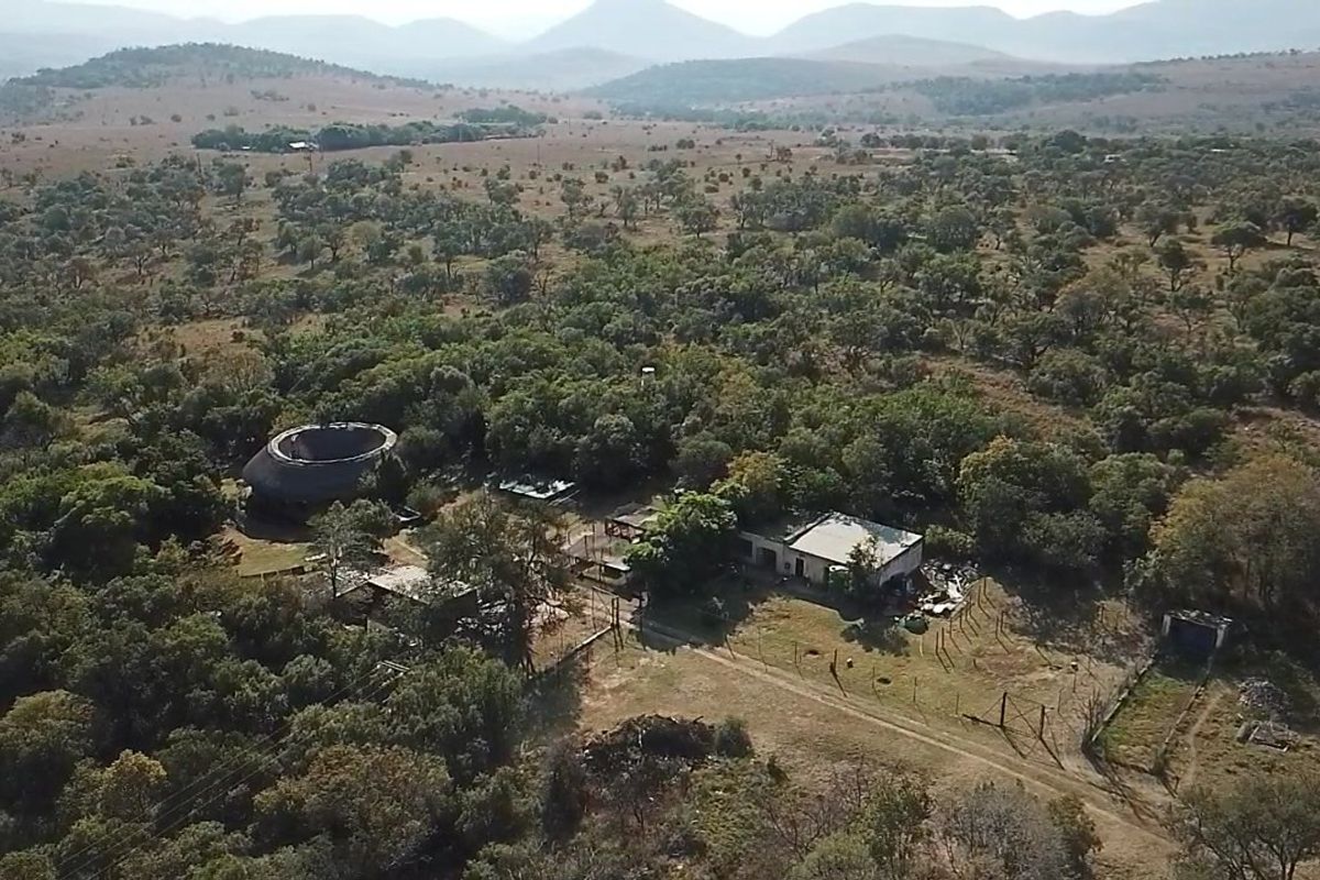 Aerial view of a rural farm property featuring multiple structures, surrounding bushveld, and natural landscape.