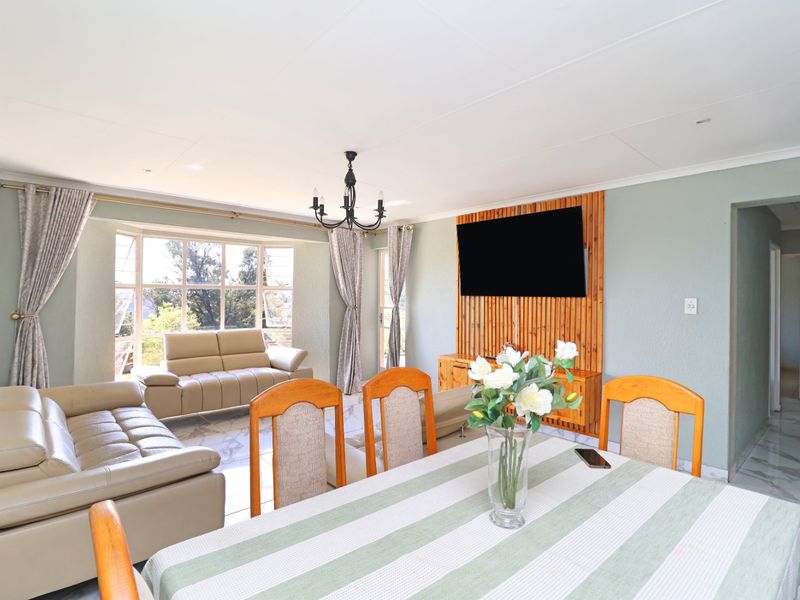 Spacious open-plan living and dining area featuring a bay window, tiled flooring, and a decorative wooden slat feature wall.