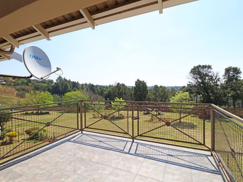 A spacious balcony featuring tiled flooring and a metal balustrade, offering an elevated view over the garden area.