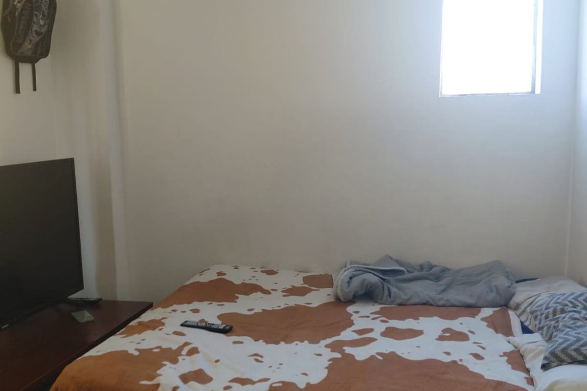 A simple bedroom featuring a single window and plain wall finishes, providing a functional sleeping space.
