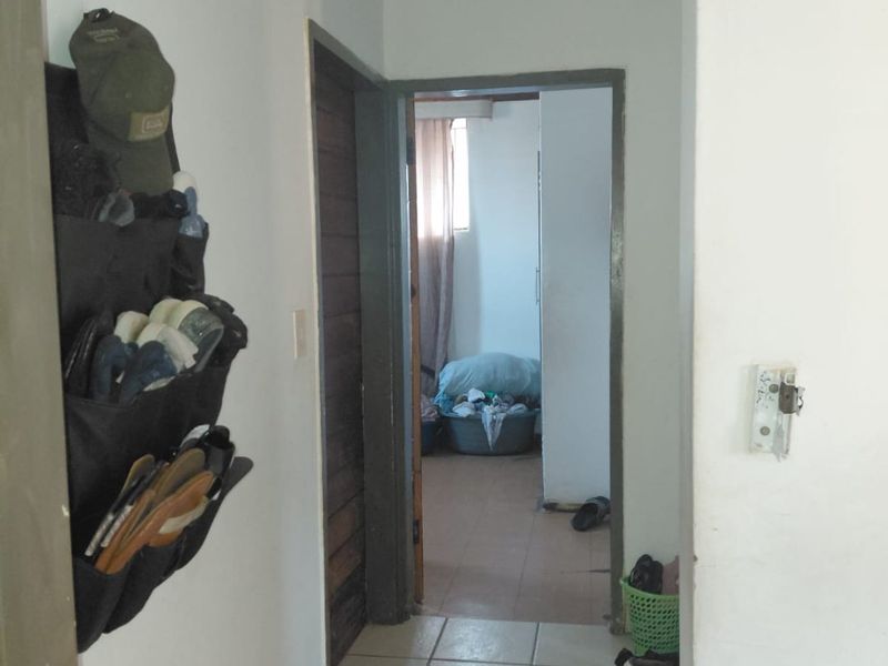 A narrow interior hallway featuring tiled flooring and access to adjacent rooms, showing signs of wear and requiring maintenance.