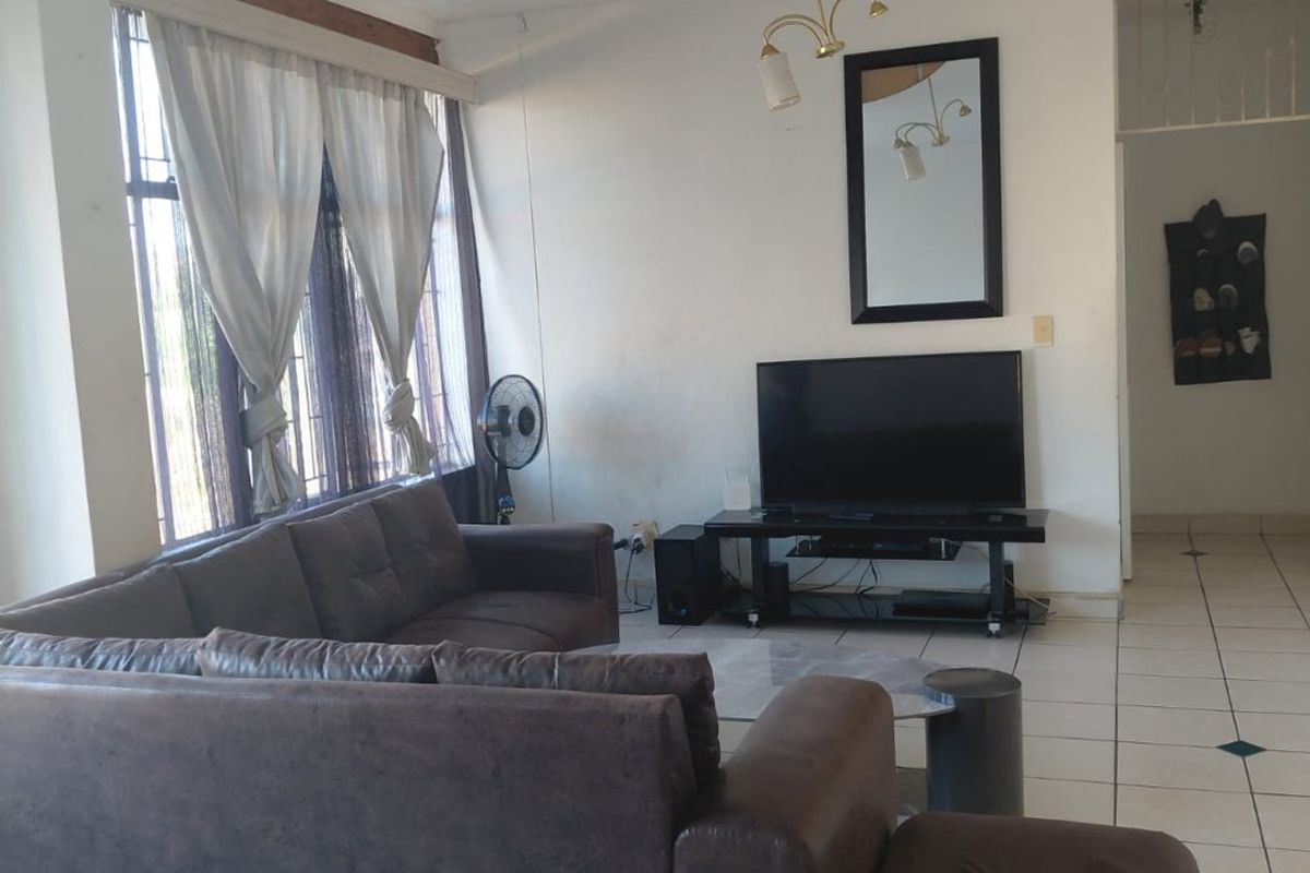 A living room featuring tiled flooring and a large window, providing a functional space with potential for cosmetic updates.