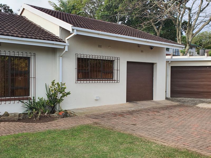 Front exterior view of the house featuring a tiled roof, brick paved driveway, and secure garage access.
