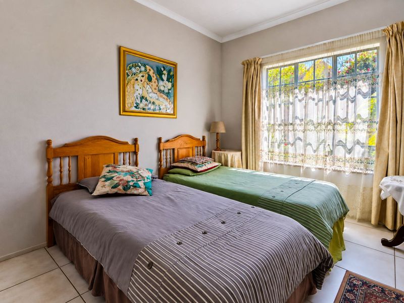 A well-lit bedroom featuring tiled flooring, neutral wall finishes, and a window with security bars, offering a functional and comfortable living space.