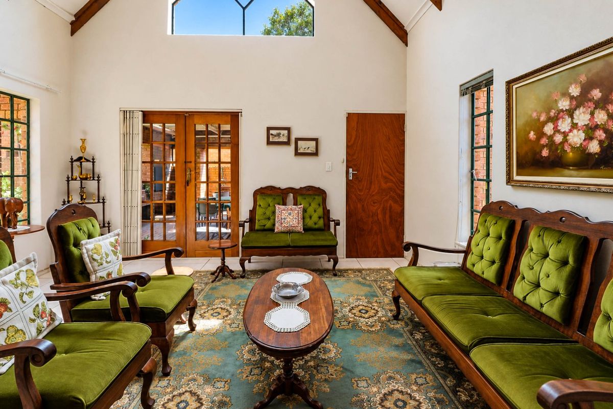 Spacious living room featuring a high vaulted ceiling with exposed timber beams, large feature window, and timber-framed glass doors leading to the patio.