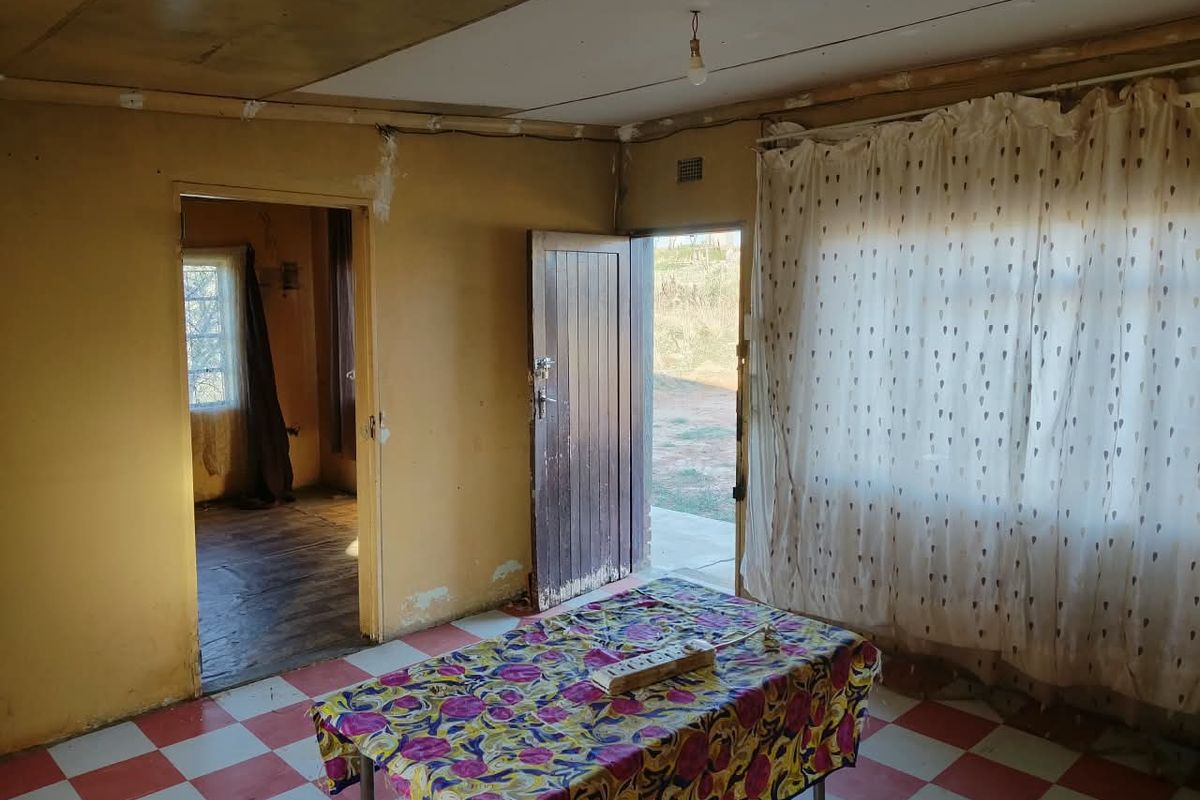 A dated living area featuring checkered tile flooring and direct access to the exterior, requiring significant renovation and cosmetic updates to restore its appeal.