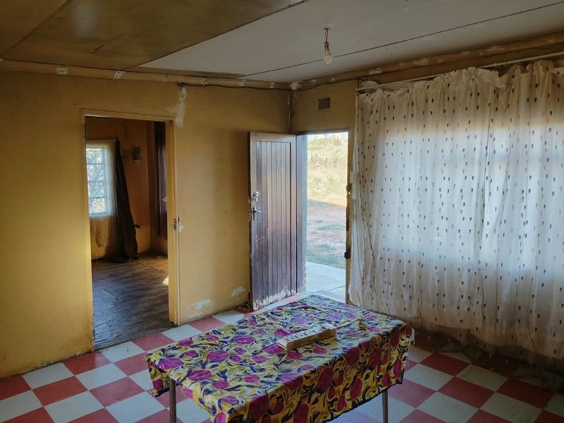 A dated living area featuring checkered tile flooring and direct access to the exterior, requiring significant renovation and cosmetic updates to restore its appeal.
