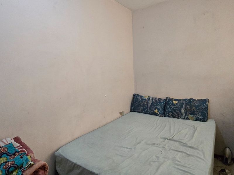 A compact bedroom featuring plain walls and a standard electrical outlet, requiring cosmetic updates to improve the overall aesthetic.