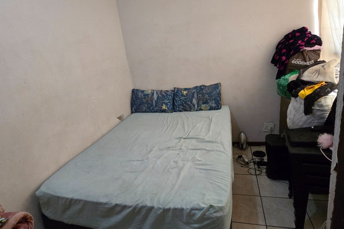 A compact bedroom featuring tiled flooring and neutral wall finishes, offering a functional space ready for personalization and cosmetic updates.