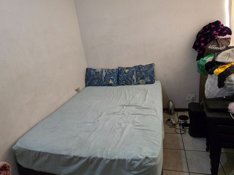 A compact bedroom featuring tiled flooring and neutral wall finishes, offering a functional space ready for personalization and cosmetic updates.