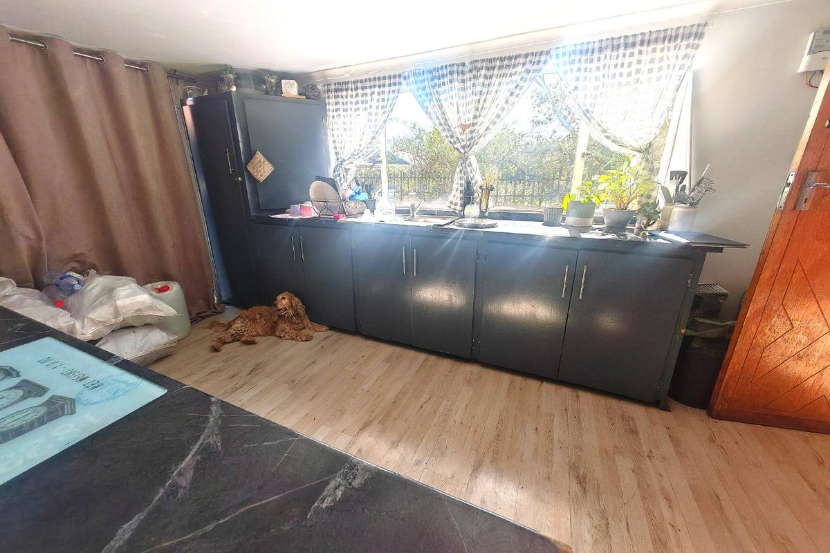 A functional kitchen area featuring dark built-in cabinetry, laminate flooring, and a window overlooking the exterior.