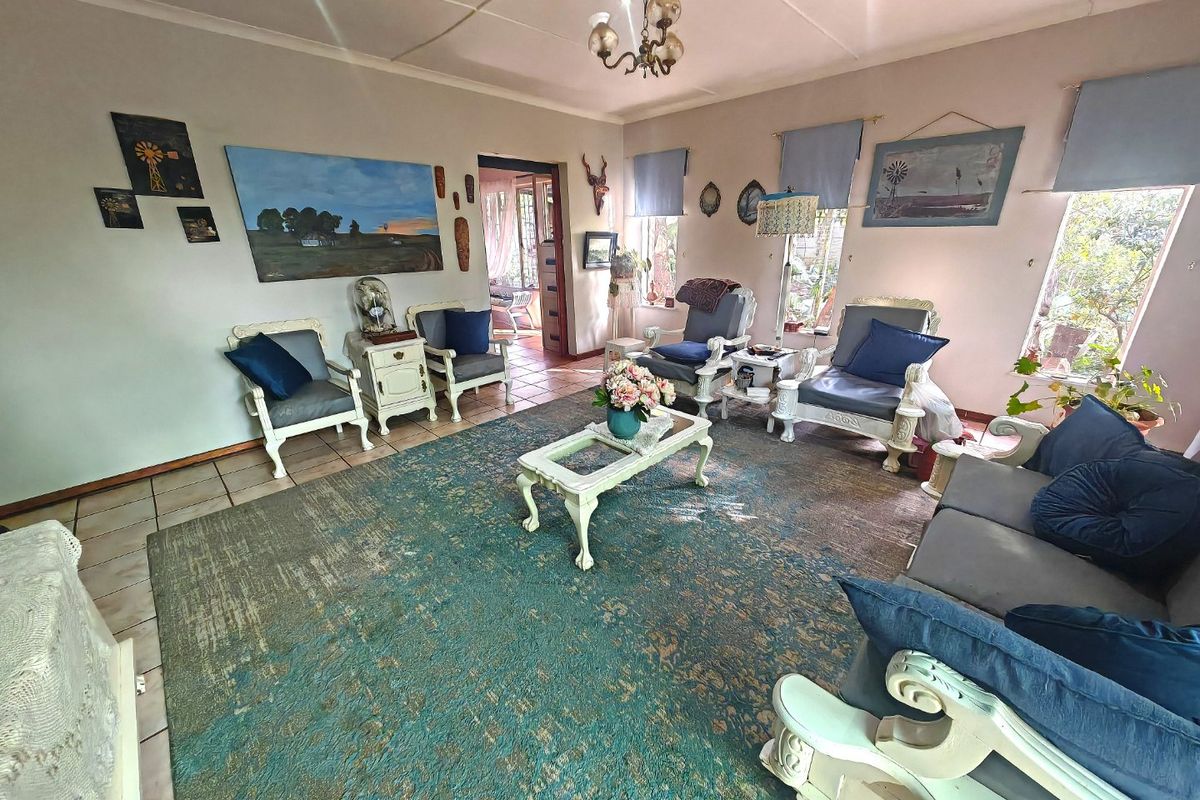 A spacious living room featuring tiled flooring, large windows providing natural light, and a central ceiling light fixture.