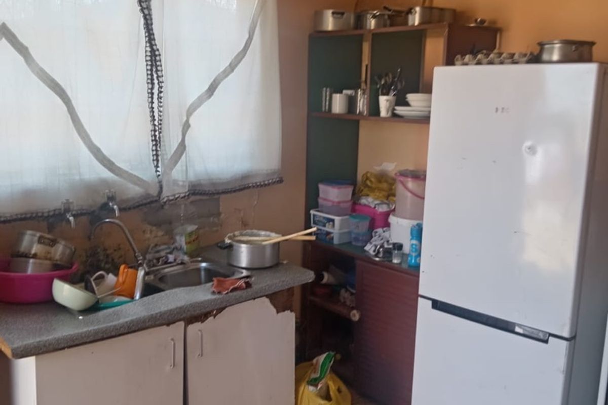 A dated kitchen area featuring basic cabinetry, a sink, and tiled flooring, currently requiring significant maintenance and cosmetic updates to improve functionality and aesthetic appeal.