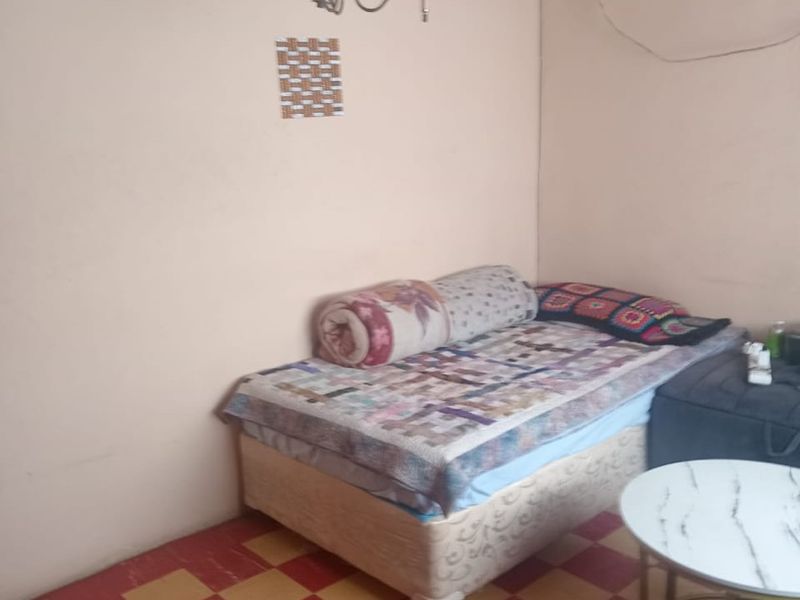 A bedroom featuring a timber ceiling, tiled flooring, and a central light fixture. The space requires cosmetic updates to improve its overall condition.