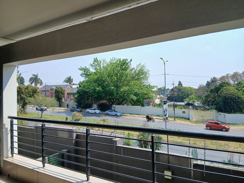 A covered balcony featuring a modern metal balustrade and tiled flooring, offering an elevated view of the surrounding street and neighborhood.